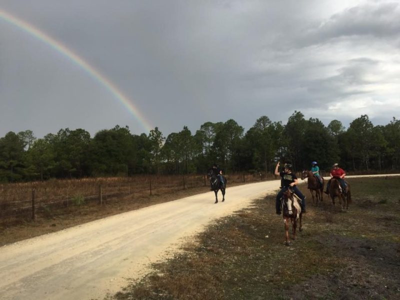 Horseback ride in front of a rainbow
